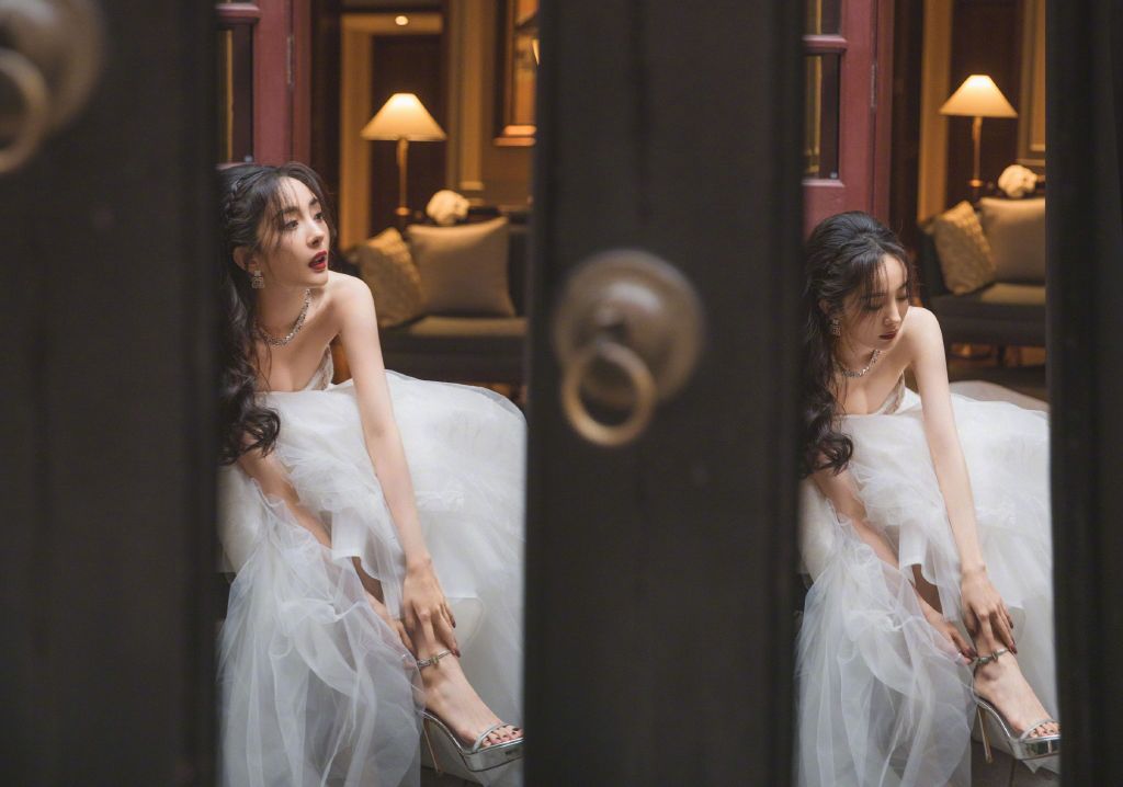 她双手抚摸自己的脚踝，优雅且美丽。